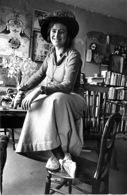 Black and white image of Naseem Khan smiling and sitting on table