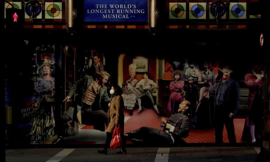 A woman wearing a face mask to curb the spread of coronavirus walks past the Sondheim Theatre in central London