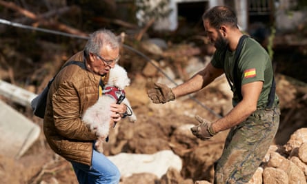A man carries a dog in Letur, Albacete province, after flash floods hit the region.