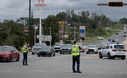 man and woman in neon vests direct traffic on highway