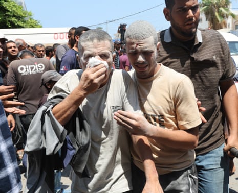 An injured Palestinian man covers his face as another walks with him at Al-Aqsa Martyrs hospital, in Deir Al-Balah on Saturday.