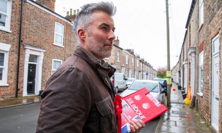 David Skaith in the street holding a clipboard with a Labour logo on it 