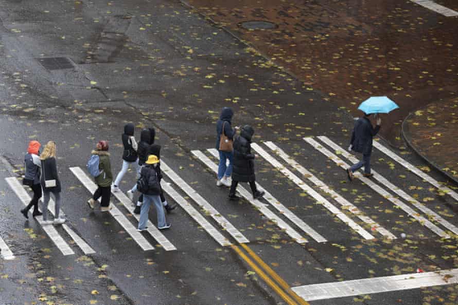 A tour group endures heavy rain as they cross a street in Seattle's Pioneer Square neighborhood.