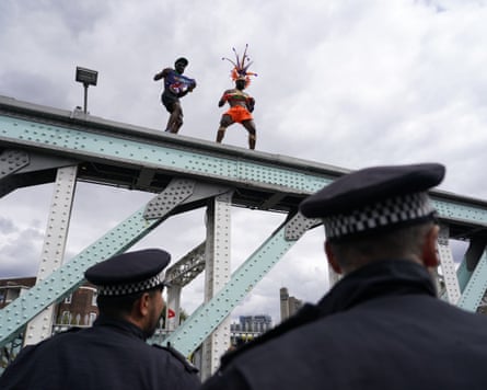Police officers watch as revellers dance on top of a railway bridge