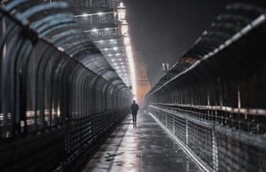 A woman walks across the Sydney Harbour Bridge in driving rain