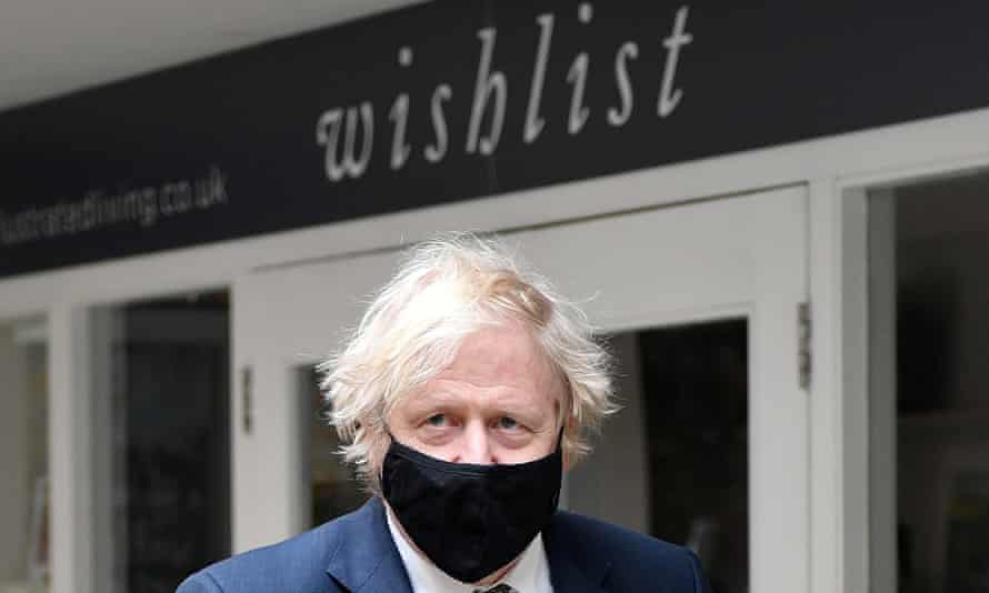Boris Johnson in a mask standing outside a business whose sign reads 'wishlist'