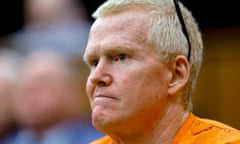 A man in an orange jumpsuit sits in court