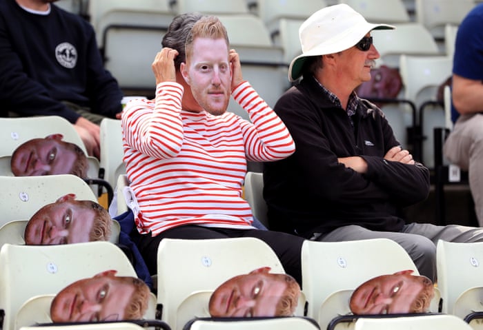 A fan tries on a face mask of England’s Ben Stokes which have been placed on the seats.