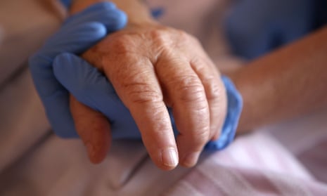 A nurse holds the hand of a patient in the palliative care unit of the the Eugenie hospital in Ajaccio, Corsica.