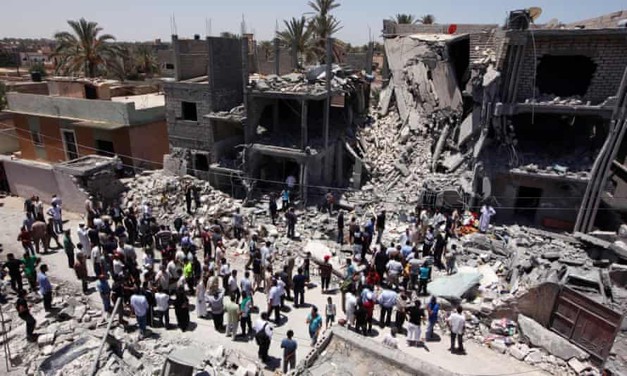 Libyans gather on June 19, 2011 next to the rubble of buildings the Libyan authorities said were damaged by airstrikes on Tripoli’s residential district of Arada