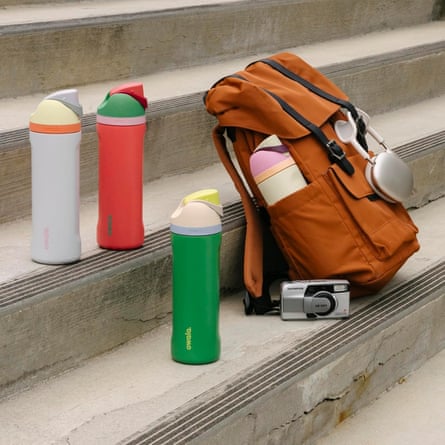 different colored water bottles sitting on steps outside next to backpack and camera