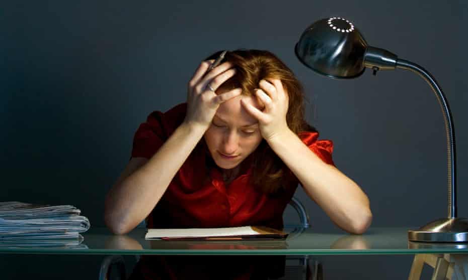 A stressed businesswoman with head in hands leaning on desk