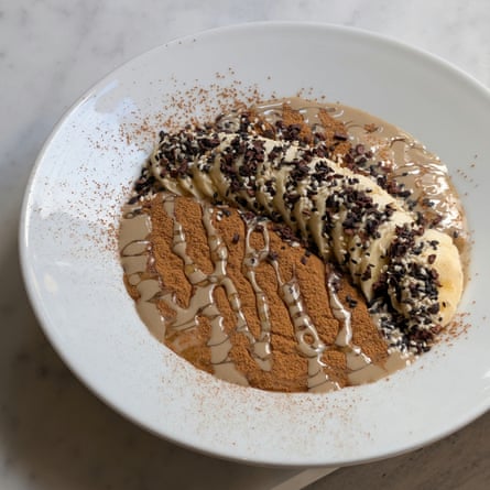 An artfully presented bowl of porridge, dusted, drizzled and topped with a whole sliced banana