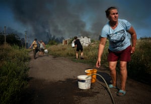 Larissa her daughter and their neighbours fill and carry buckets of water