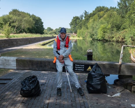Steve Warmer, on Community Payback, stands by a canal with a litter picker and full trash bags