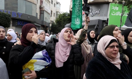Protesters in Ramallah – a large group of women seen at the front of a crowd, wearing headscarves and shouting and carrying flags and banners