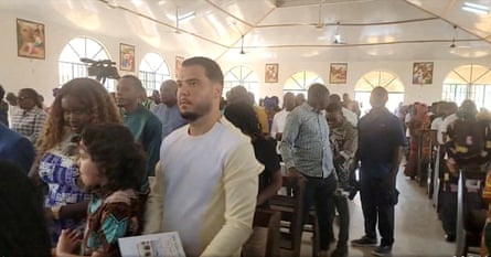 A man and woman standing in the front pews of an African congregation in church.