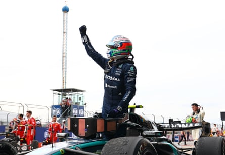 Andrea Kimi Antonelli raises his fist in celebration while standing on his F1 car.