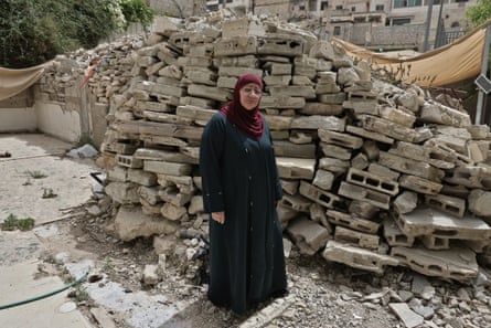 it is heaped neatly in a tall pile. She wears a black robe and a dark red headscarf.