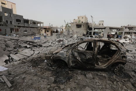 A burnt-out car is pictured in Nuseirat with destroyed buildings in the background on Thursday.