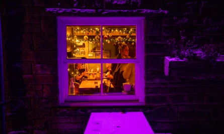 A window in purple light on to a room in the pub where people are talking and drinking