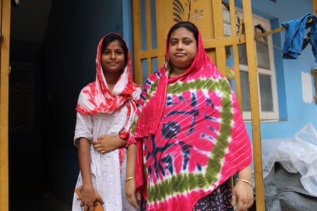 A woman in a brightly coloured headscarf stands with a young girl in a doorway.