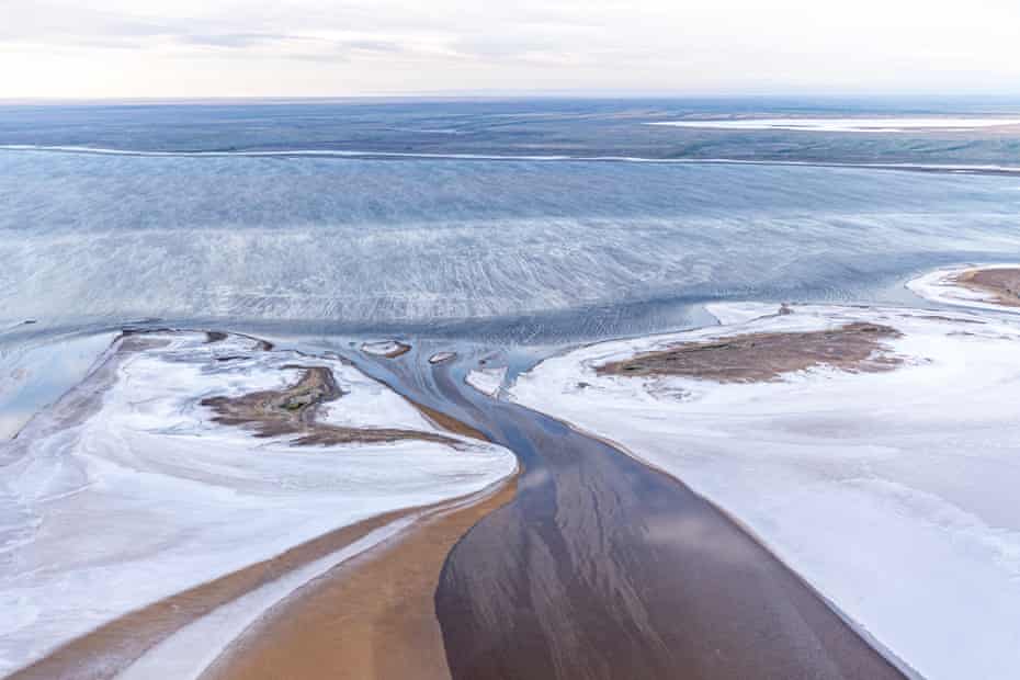 Aerial view showing water flowing over edge of salt pan into South Lake Eyre; the water being the result of unusually high local desert rainfall. South Lake Eyre, South Australia, Australia. March 2022