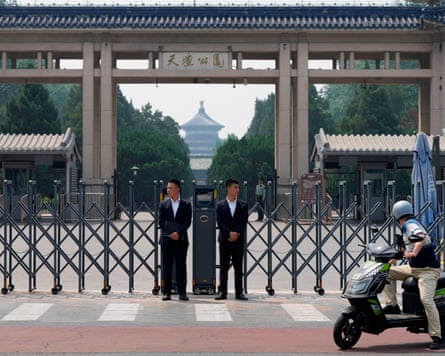 Two people stand in front of closed gates near the Temple of Heaven