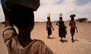 Women carrying heavy jugs filled with water.