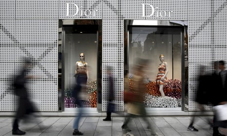 People walk past a Dior store