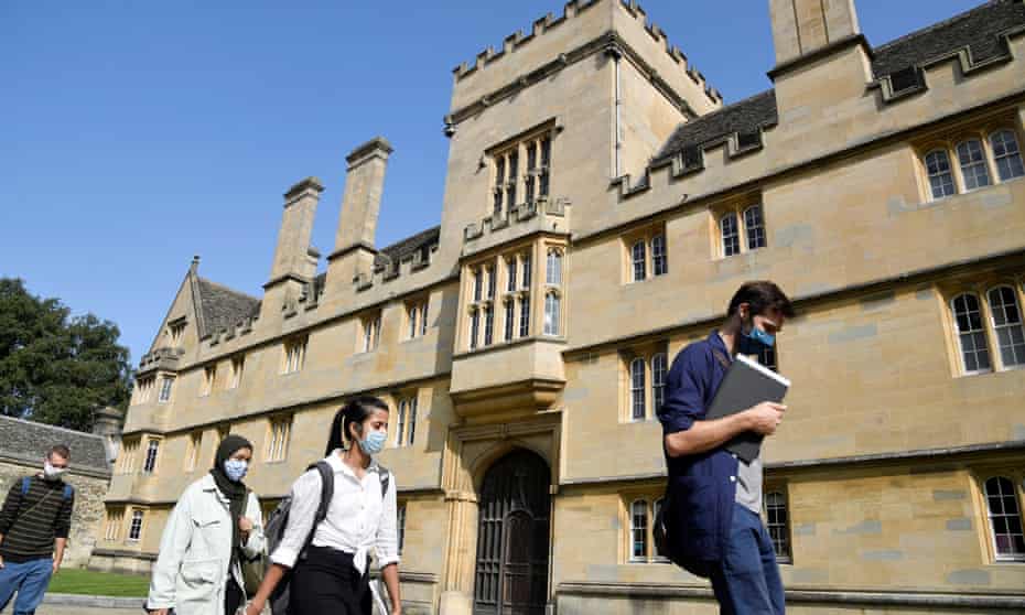 People in masks walk past Wadham college Oxford