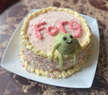 A round ornately multi-pastel-coloured iced frog on a cake