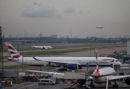 A passenger plane approaches a runway at Terminal 5 of Heathrow where British Airways planes are parked.