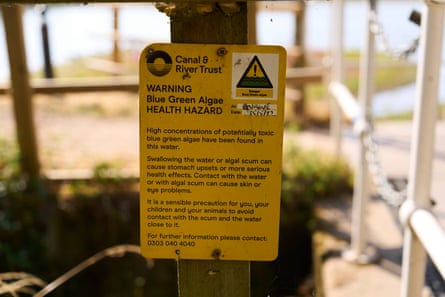 Yellow sign with warning with barriers and water out of focus in background