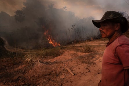 A man looks on as the forest burns