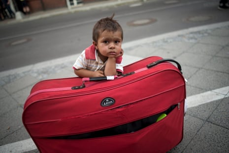 A migrant boy waits at his parents’ suitcase as they  apply for asylum in Berlin