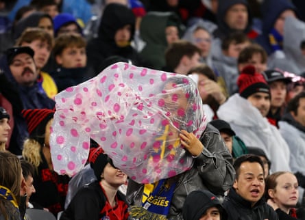 Sports fans at a stadium try to shelter from a storm.