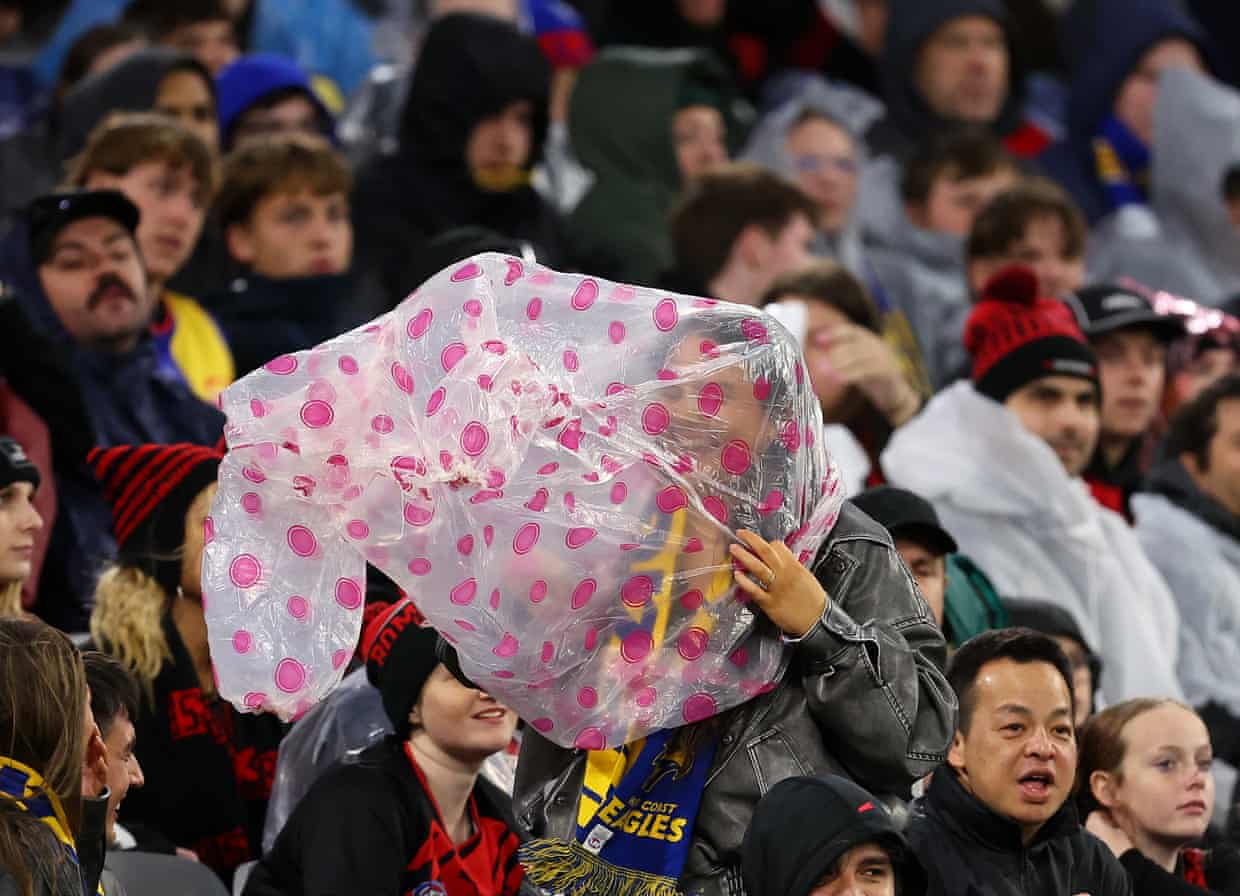 Sports fans at a stadium try to shelter from a storm