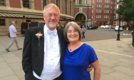 Christopher Larkin and Patricia Larkin with their arms round each other, he wearing full white-tie and a buttonhole, she wearing a blue dress, with the Albert Hall int he background