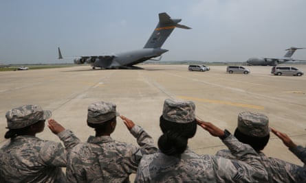 US soldiers salute as vehicles carry away the remains.