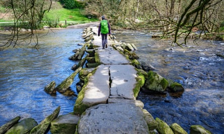 a walker crosses the slabs of stone that span the river