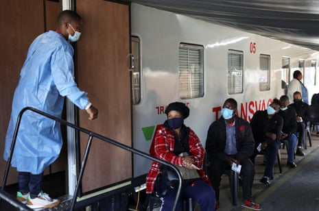 A health worker talks to people as they wait to register next to the Transvaco coronavirus disease (COVID-19) vaccine train at the Springs train station on the East Rand, South Africa.