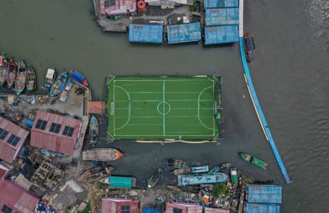 Overhead view of a floating football pitch surrounded by boats, buildings and water