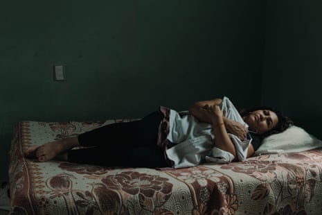 Esperanza Pacheco in the room that her family occupies when they visit her in León, México. She hugs the clothes that her husband left on his last visit.