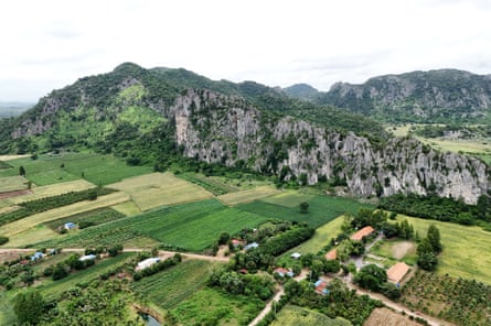 An aerial view of rocky limestone hills rising above green farming fields.