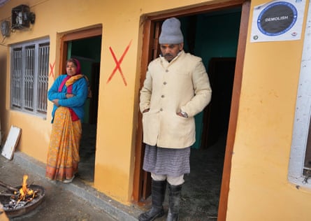 Chandra Pandey and his wife outside their home, which has a red X painted on it, meaning it will be demolished.