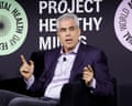 Jonathan Haidt makes a pointing gesture with both hands as he speaks on stage, with a Project Health Minds banner behind him
