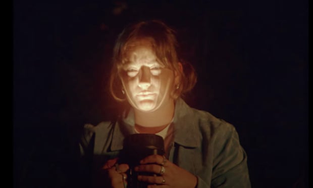 Katy J Pearson in the Howl music video shining a torch on to her face.