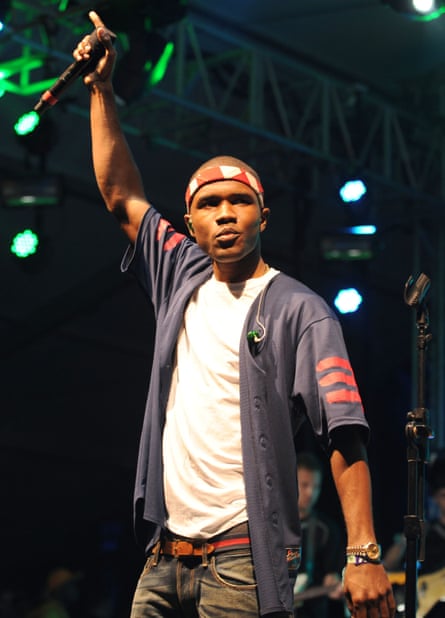 He poses on stage, one arm raised, holding his mic
