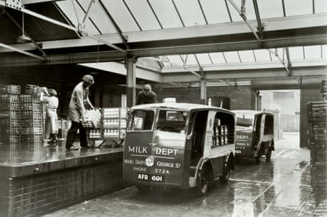Workers loading milk on to electric delivery van.